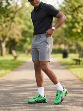 Vs1 Contact Mens Sneakers – Grey tailored athletic shorts combined with a black polo shirt that has green piping on the collar, worn with high-quality white crew socks for a sporty weekend vibe.