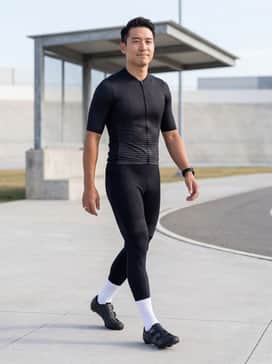 A sleek aerodynamic black-and-grey gradient cycling jersey paired with high-compression bib shorts and white crew-length performance socks for a classic pro-level look.