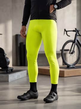 A high-visibility neon yellow thermal cycling jacket worn over a base layer with black thermal tights for early morning winter training rides.