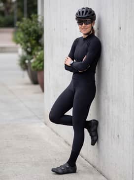 An all-black 'stealth' kit including a matte black aero helmet, dark-tinted wrap-around sunglasses, and a minimalist black jersey for a cohesive, powerful aesthetic.