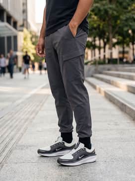 An urban techwear ensemble with tapered black cargo pants, a crisp white long-sleeved base layer, and a structured olive green windbreaker for a functional street aesthetic.