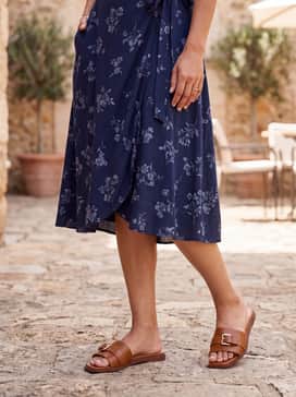 A navy blue floral midi-length wrap dress with a light denim jacket for a breezy, feminine look during a daytime garden party.