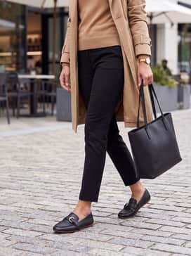 Black skinny jeans worn with a camel-colored cashmere turtleneck and a classic tan trench coat for a timeless urban look.