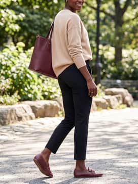 Slim-fit black cigarette pants matched with an oversized beige cashmere knit and a matching burgundy leather tote bag for a tonal accessory moment.