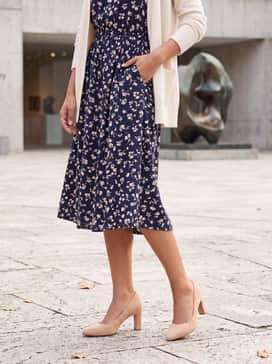 A navy blue floral midi dress with a cinched waist and a cream-colored cardigan for a soft, feminine daytime ensemble.
