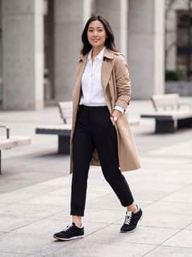 High-waisted black skinny jeans paired with a tucked-in white linen button-down and a tan trench coat for a sophisticated, monochrome city look.