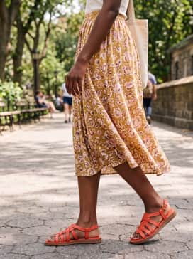 Womens Kami Thong Sandals – A floral print midi skirt in shades of yellow and pink with a simple white tank top for a bright, feminine daytime outfit.
