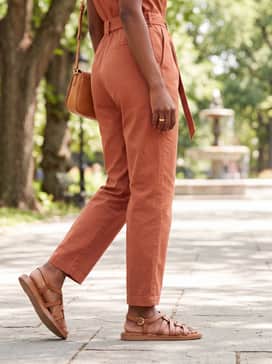 Womens Kami Thong Sandals – A terracotta-toned cotton jumpsuit with a cinched waist and a matching tan leather crossbody bag, perfect for a day of seaside sightseeing.