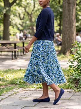 Womens Nicolette Ballet Flats – A floral print A-line midi dress in shades of blue and green, complemented by a fitted navy cardigan for a feminine and classic aesthetic.