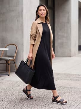 Womens Riginalgrand Peyton Flatform Sandals – A monochromatic black jersey maxi dress paired with a lightweight tan trench coat and a structured leather tote bag for a sleek, travel-ready ensemble.