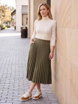 A pleated olive green midi skirt combined with a fitted cream turtleneck sweater for a balanced, feminine-meets-masculine ensemble.