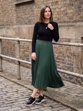 Womens Riginalgrand Platform Wingtip Oxfords – A pleated midi skirt in a forest green hue, a fitted black bodysuit, and a delicate gold pendant necklace for a balanced feminine-meets-masculine aesthetic.