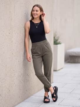 High-waisted olive green joggers and a black fitted bodysuit, topped with a delicate gold necklace.