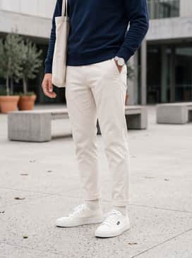 York – Olive green slim-fit chinos paired with a navy blue crewneck sweatshirt and a black canvas tote bag for a classic collegiate-inspired look.