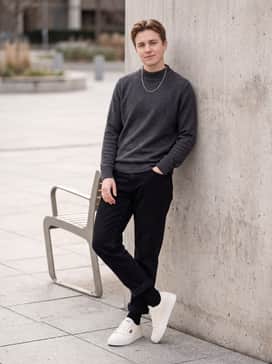 York – Relaxed-tapered black denim trousers, a charcoal grey mock-neck knit top, and a minimal silver chain to create a sleek monochromatic streetwear vibe.
