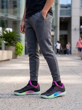 Tapered tech-fleece joggers in charcoal grey with a fitted black hoodie featuring minimalist neon green graphics.