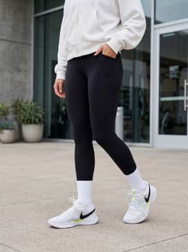 A trendy athleisure look with high-waisted black leggings, a neon yellow sports bra to pick up the shoe's accents, and an oversized white zip-up hoodie.