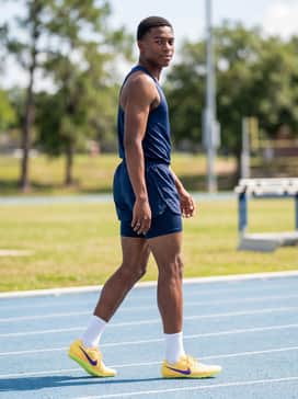 Zoom Ja Fly 4 – A neon lime green mesh racing jersey that coordinates with the spike plate, paired with navy blue athletic shorts for a high-visibility training outfit.