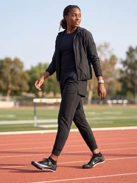 A fitted long-sleeve base layer in a bold primary color under a lightweight windbreaker, paired with tapered athletic joggers for warm-up drills.