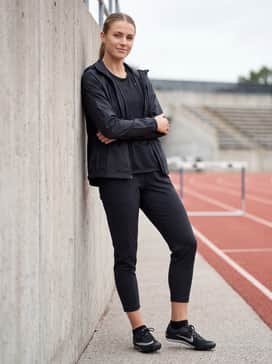 A sleek, black weather-resistant windbreaker over a breathable mesh base layer, combined with tapered joggers for track-side warm-ups.