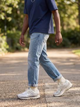 Straight-leg light-wash denim jeans cuffed at the ankle, a simple navy blue boxy tee, and a silver chain necklace to complement the shoe's metallic details.