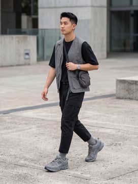 Zoom Vomero Roam – Tapered black ripstop cargo pants, a black technical tee, and a matching grey utility gilet for a cohesive urban techwear ensemble.